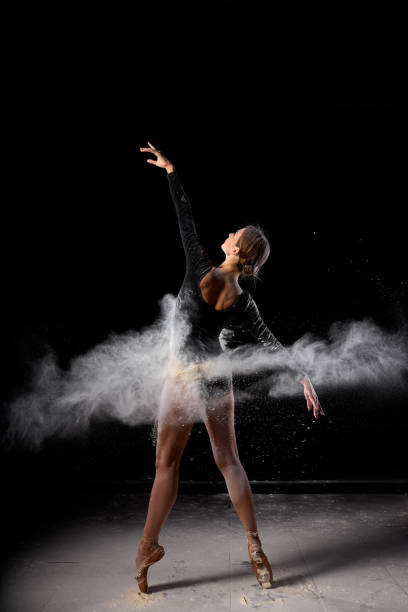 istock Ballerina dancing with flour on black studio background. Dancer in black bodysuit 1884761229