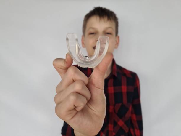 istock Man smiling holding dental aligner retainer in hand invisible 1884768612