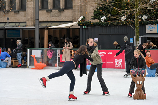 Stockholm, Sweden - February 03, 2018: Front view of a young man skating at a public ice skating rink outdoors in the city center of Stockholm february 03, 2018. Incidental people in the background.