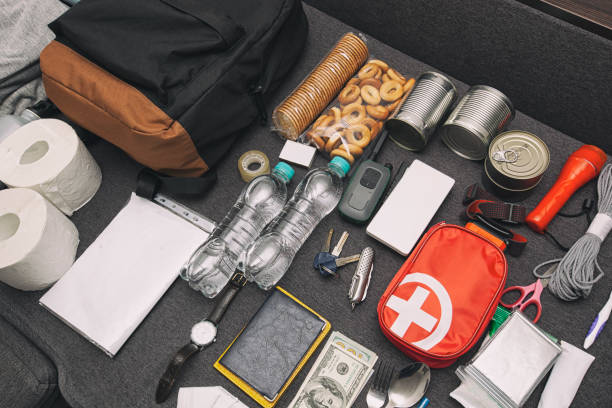 istock Emergency backpack equipment organized on the table. Documents, water,food, first aid kit and another items needed to survive. 1884792514