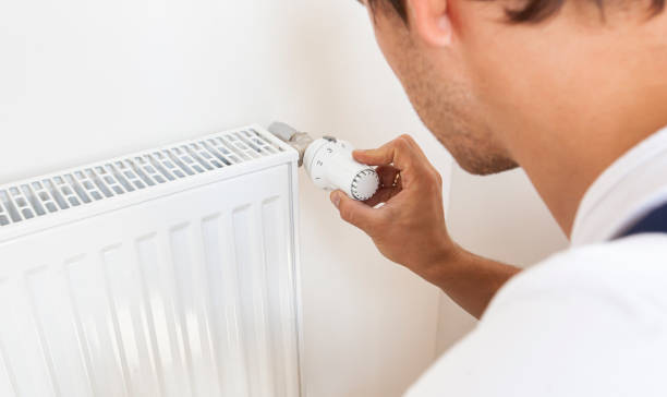 istock man increase temperature of radiator by adjusting thermostat 1884798324