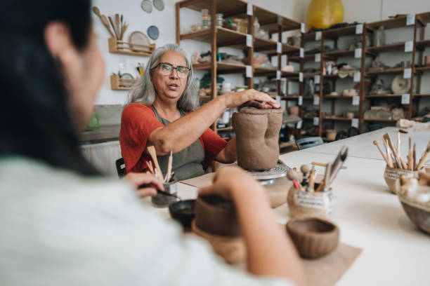 istock Senior woman talking with her friend on pottery class at a ceramics workshop 1884803301