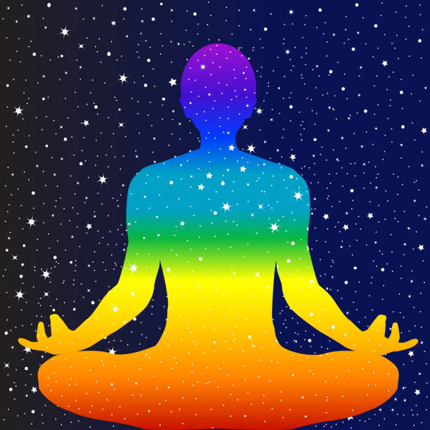 istock Meditating Chakra colors man sitting in lotus position against a starry dark blue  sky 1884828263