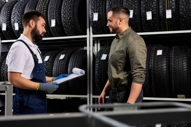 istock affable auto mechanic in uniform help customer with choice 1884832621
