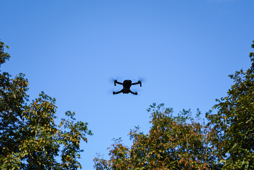 A camera drone is flying for recording the VDO with blue sky background. Technology gadget object photo, selective focus.