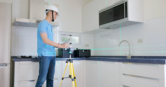 asian male home inspector is using laser level to check kitchen interior