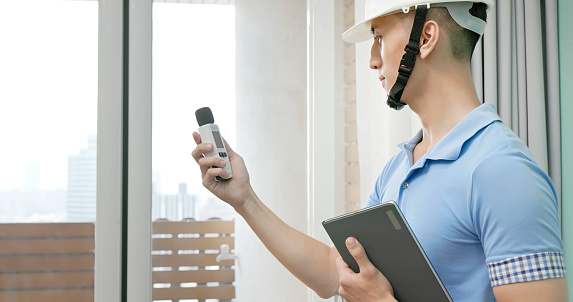 asian male home inspector is using sound level meter to check the interior noise degree