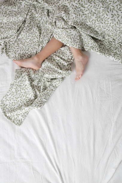 istock Child feet under cotton bedcover under soft morning light 1884894813
