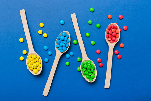 delicious colorful sweet candies on spoon on colored background . Confectionery decor top view with copy space.