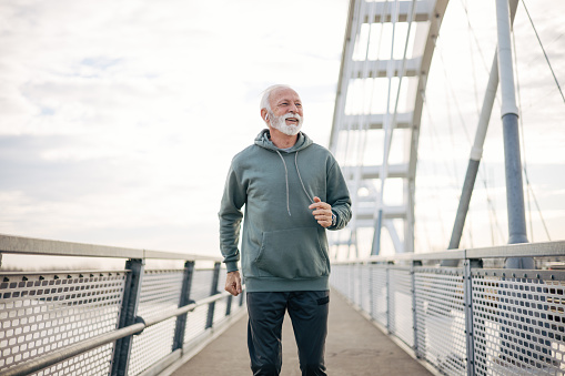 Senior man jogging on bridge