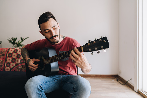 Young man playing the guitar in the apartment