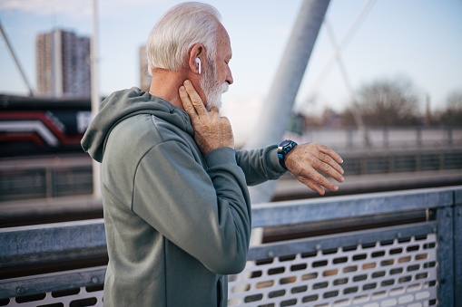 Senior man measuring heart rate pulse on his neck and looking on watch