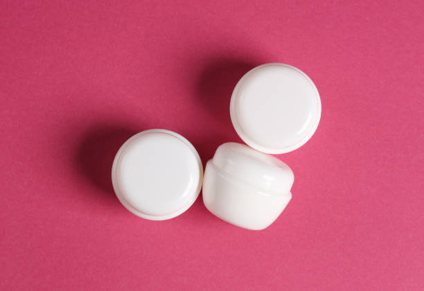 istock White cream jars on pink background. Mockup, template for design. Top view 1884960446