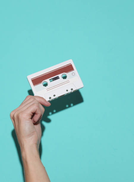 istock Female hand holding retro 80s audio cassette on blue background with shadow 1884960851