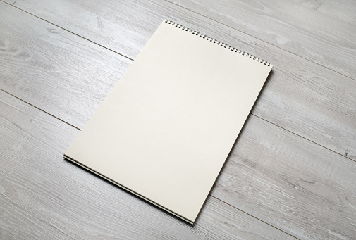 Blank notepad for sketching on wooden background. Sketchbook with spiral. Free space.