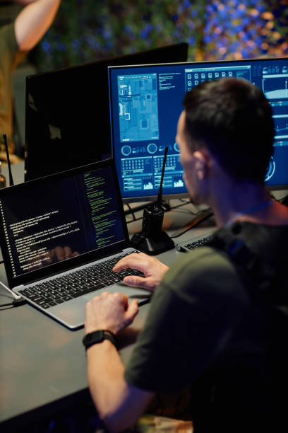 istock Young male military officer in uniform looking through data on laptop screen 1884974300