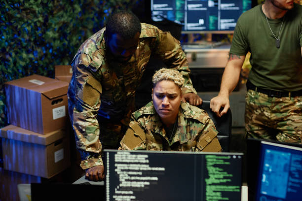 istock Serious female officer in camouflage uniform looking at computer screen 1884974316