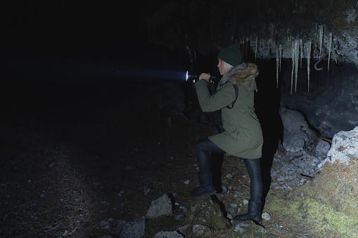 A girl with a flashlight in her hand in a dark forest near a destroyed bunker. High quality photo