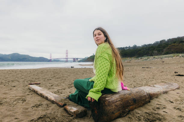 happy woman contemplating baker beach in san francisco, california listening to music - golden gate bridge audio стоковые фото и изображения