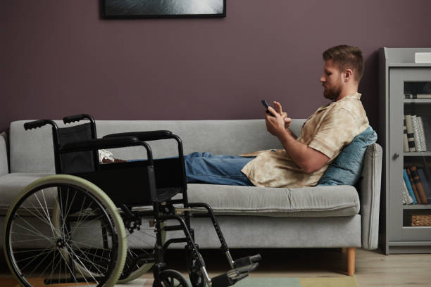 mann mit behinderung entspannt sich zu hause auf der couch - accessability stock-fotos und bilder