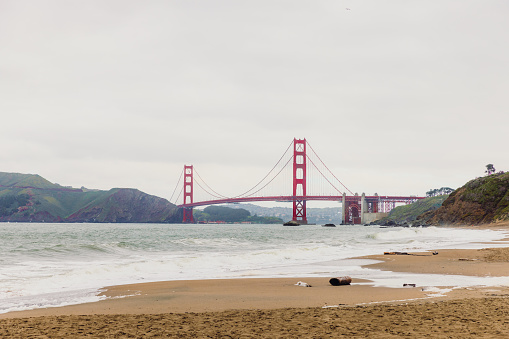 Scenic view of tranquil spring day at the central bridge with wavy ocean, green hills and big red bridge in San Francisco city, California