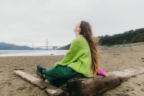 happy woman contemplating baker beach in san francisco, california listening to music - golden gate bridge audio photos et images de collection