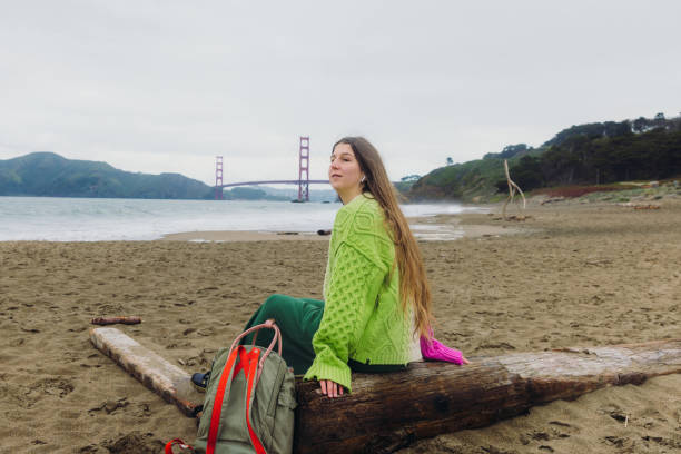 happy woman contemplating baker beach in san francisco, california listening to music - golden gate bridge audio fotografías e imágenes de stock