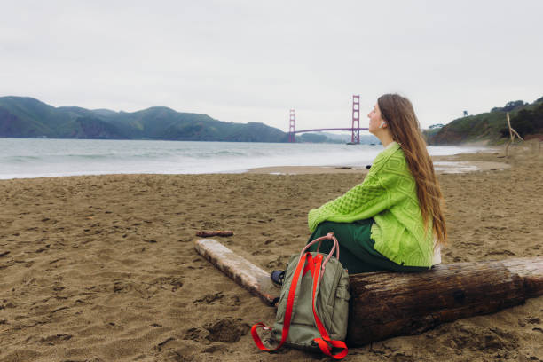 happy woman contemplating baker beach in san francisco, california listening to music - golden gate bridge audio fotografías e imágenes de stock