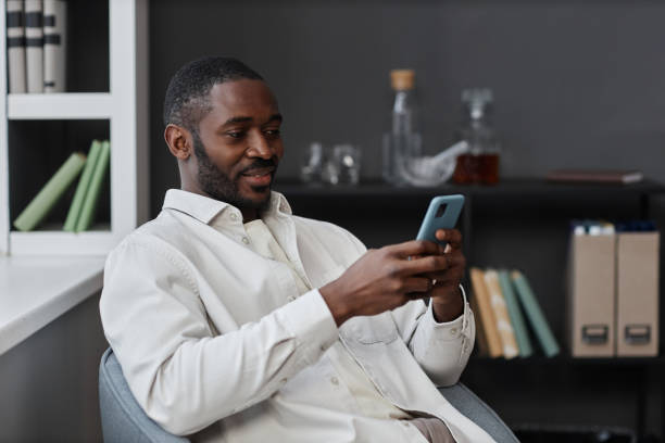 istock Black Man using Smartphone Relaxing in Chair 1885094881
