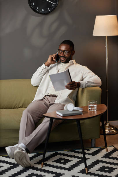 istock Black Man Speaking on Phone Relaxing on Couch in Office 1885094891