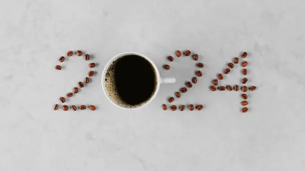 Welcome to 2024 spelled out with fresh coffee beans and brewed coffee in a cup on a marble countertop