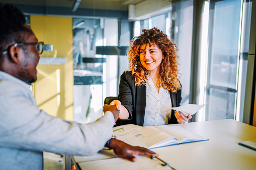 Young  business partners shaking hands after a business meeting or negotiation