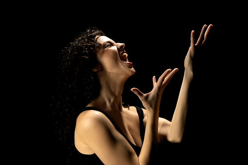 Tears of Despair: Woman's Silhouette with Raised Hands on Dark Studio Background