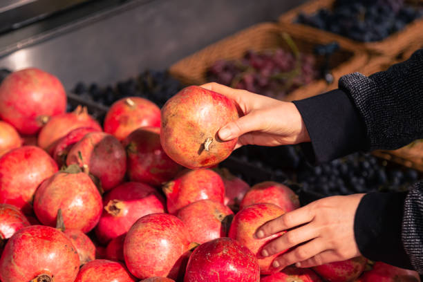 istock A woman chooses pomegranate fruit at a grocery store. 1885149711
