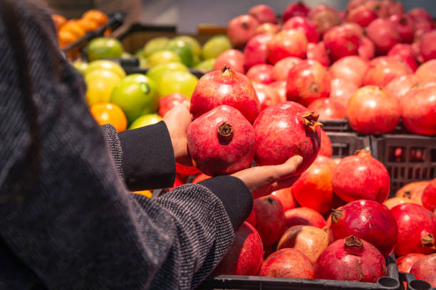 istock A woman chooses pomegranate fruit at a grocery store. 1885149712