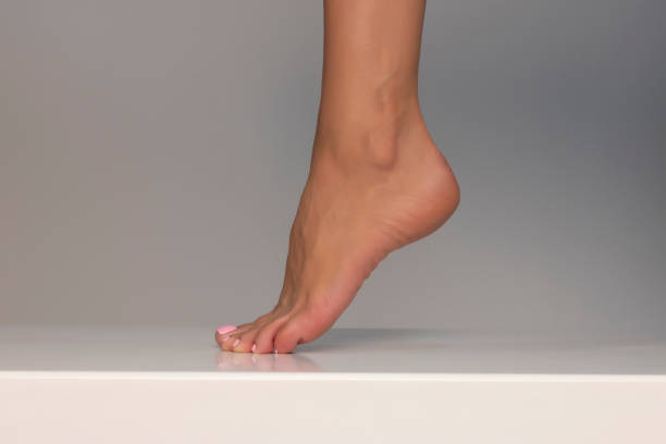 Closeup shot of healthy beautiful female feet. Health and beauty concept. Side view of human foot on grey background stock photo