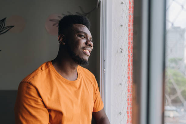 istock Mid adult man looking through window at home 1885217686