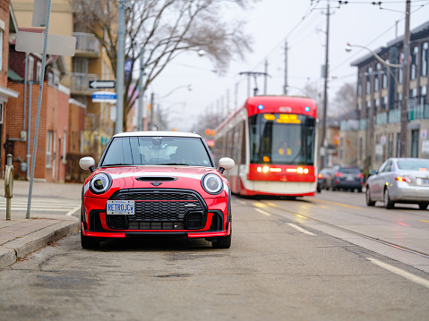 Toronto, Ontario, Canada- December 24, 2023.  Chili red colour MINI COOPER on the streets of Toronto East side, Canada. Foggy morning with overcast sky.  This is the third generation model F56 JCW, since BMW took over iconic brand of MINI. MINI featured in the photo is John Cooper Works model, the most powerful 2 door version. For the first time, this compact car features engine build and designed by BMW, and packs even more power and torque than previous models since 2002 to present. Original design clues and themes are still present on this brand new model. Mini has been around since 1959 and has been owned and issued by various car manufacturers.