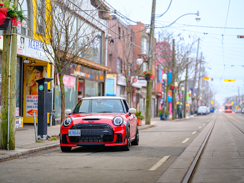 Toronto, Ontario, Canada- December 24, 2023.  Chili red colour MINI COOPER on the streets of Toronto East side, Canada. Foggy morning with overcast sky.  This is the third generation model F56 JCW, since BMW took over iconic brand of MINI. MINI featured in the photo is John Cooper Works model, the most powerful 2 door version. For the first time, this compact car features engine build and designed by BMW, and packs even more power and torque than previous models since 2002 to present. Original design clues and themes are still present on this brand new model. Mini has been around since 1959 and has been owned and issued by various car manufacturers.