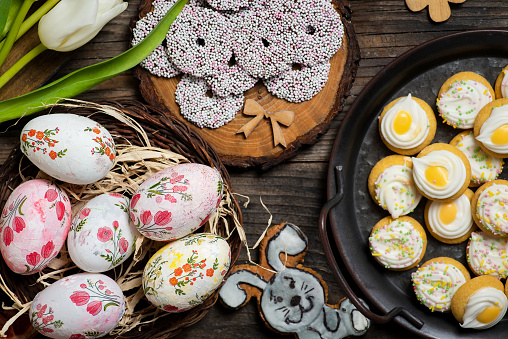 Festive table with colorful Easter decoration, Easter eggs, flowers and delicious sweet biscuits