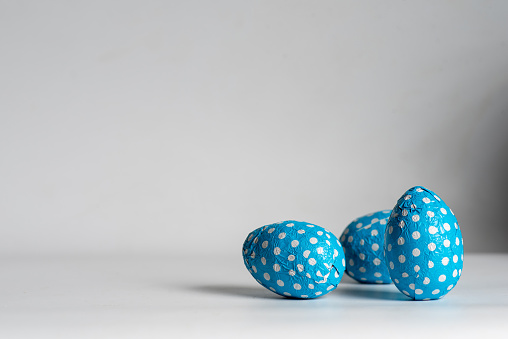 Chocolate Easter eggs in decorative blue paper isolated on white. With copy space