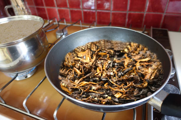 Assorted forest mushrooms and risotto are being cooked on a gas hob