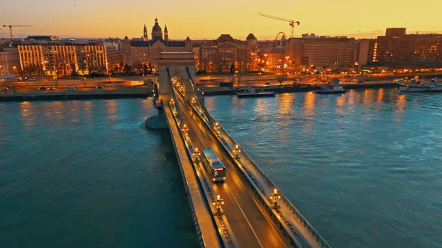 AERIAL Footage of Illuminated Széchenyi Chain Bridge over Danube River with Historic Buildings in Background at Budapest,Hungary