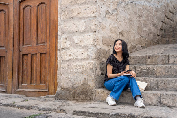 istock Young Latin female tourist taking a break while sightseeing in Casa Embrujada, Yanahuara, Arequipa, Peru 1885295018