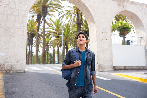 Mid-shot front view of young Latin male tourist taking a walk while sightseeing in Mirador de Yanahuara, Arequipa, Perú