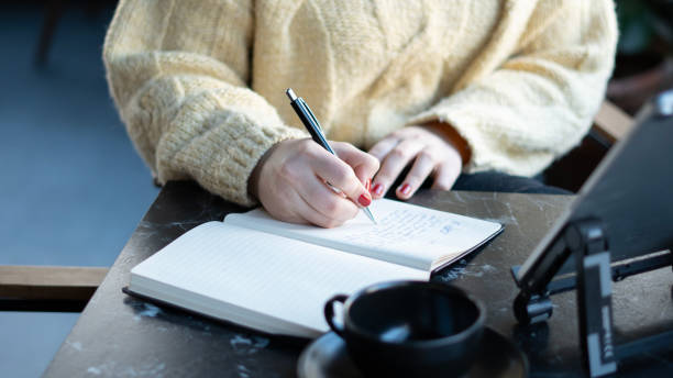 istock Woman's hand using digital tablet and writing in notebook in cafe 1885326434