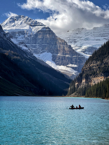 Medium shot of a family in a canoe silhouetted against the dramatic backdrop of Lake Louise and its dramatic snowcapped mountains