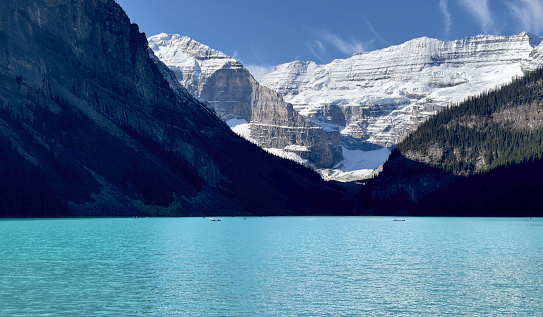 Medium shot of canoes dwarfed by the snowcapped mountain range of Canada's Lake Louise