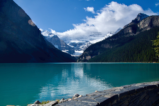 Wide shot of the snowcapped mountain range framing Canada's spectacular Lake Louise (also reflected in the lake)