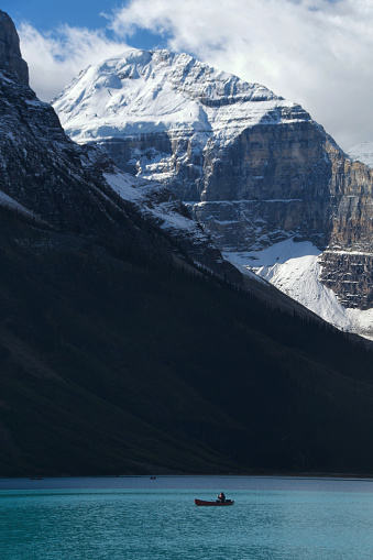 Close-up of a man in a canoe dwarfed by the massive Mount Lefroy in Canada's Lake Louise
